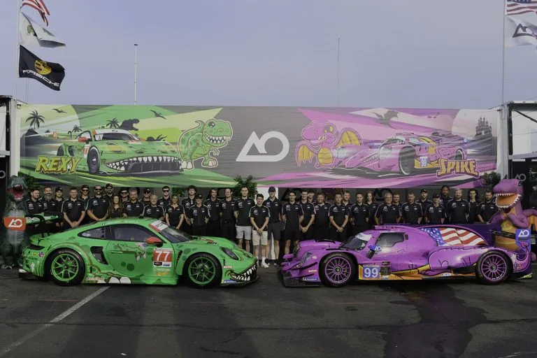 AO Racing team standing behind Rexy and Spike race cars