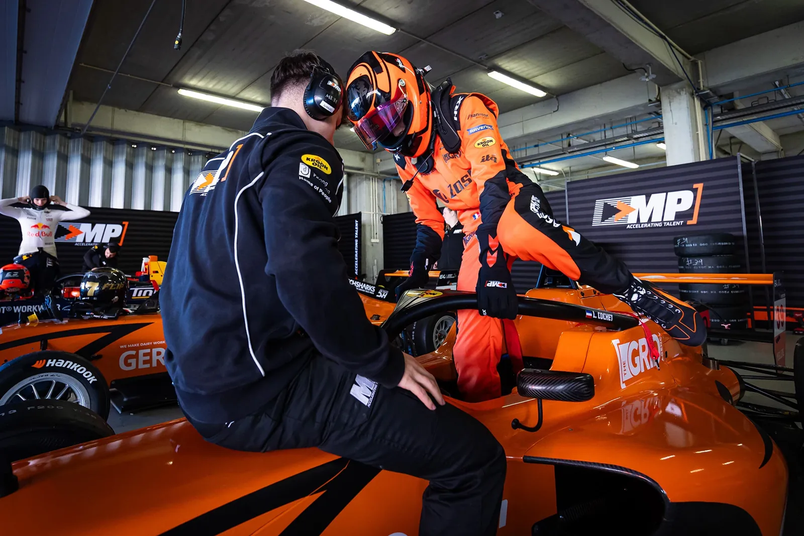 MP Motorsport driver speaking with a team member beside the car in the garage